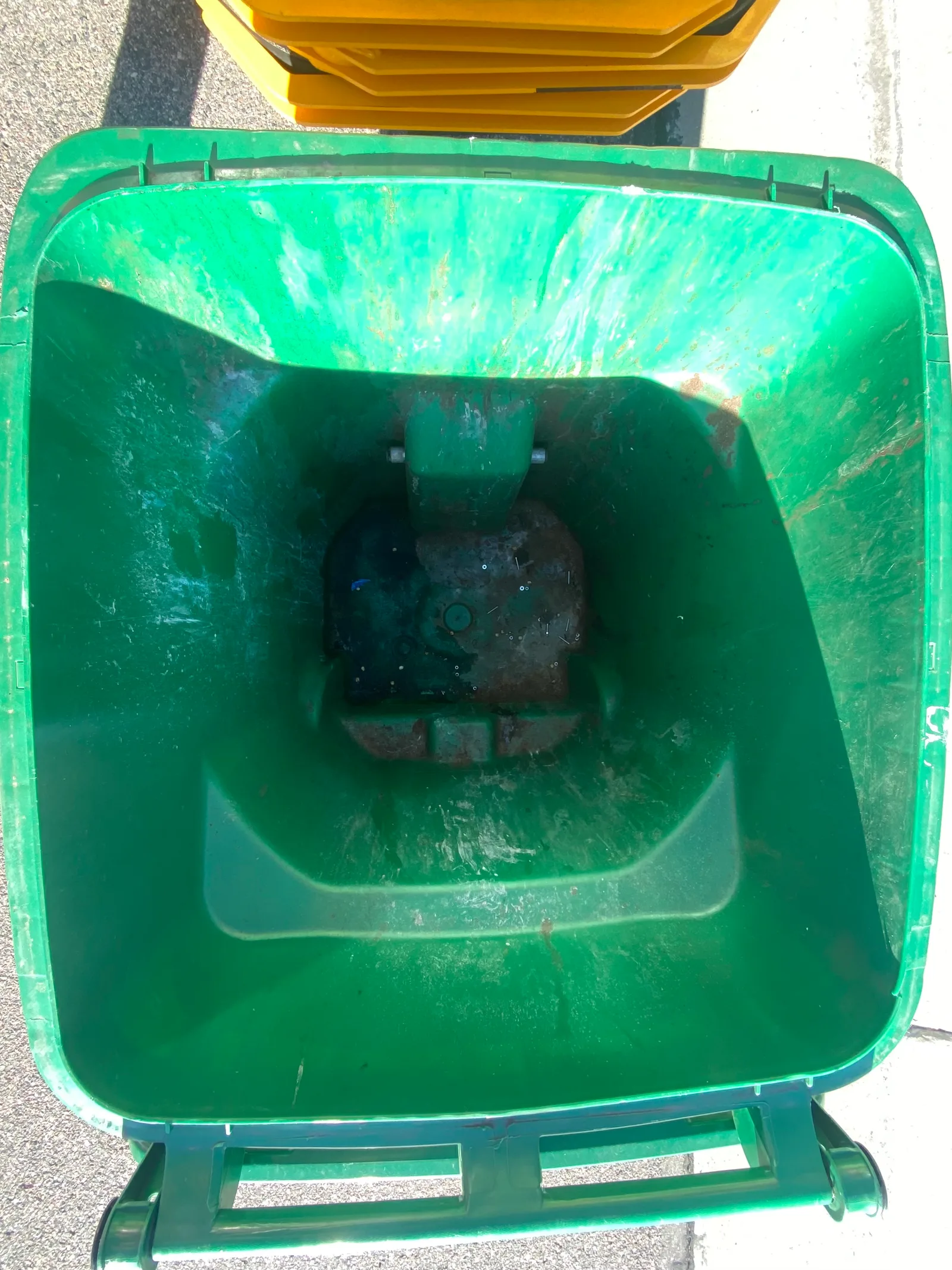 Green curbside trash bin with grime, residue, and odor buildup before professional Britebin cleaning